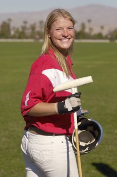 Portrait of happy female player holding polo stick