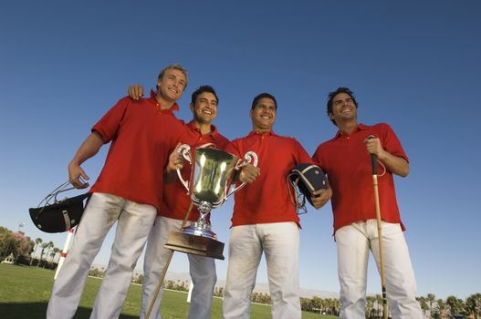 Low angle view of male polo players with trophy on field