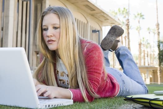 Beautiful young female student using laptop at college campus
