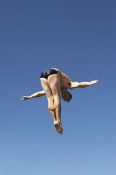 Diver diving in midair against clear sky