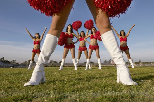 Cheerleader in white knee high boots low section with cheerleaders behind