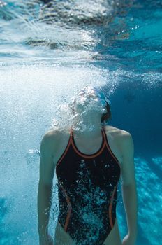 Active female diver swimming while holding breath underwater