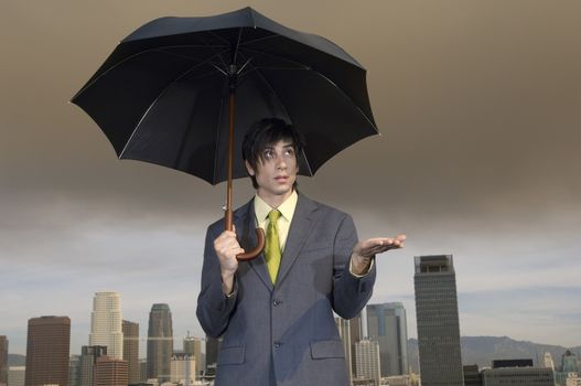 Caucasian businessman with an umbrella checking if its raining
