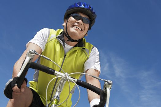 Low angle view of senior man riding bicycle against sky