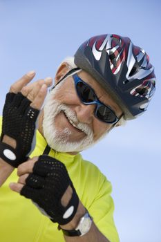 Portrait of a happy senior man wearing gloves against sky