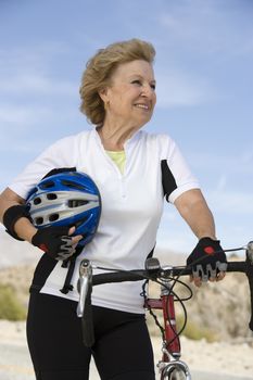Portrait of a happy senior woman standing by bicycle and looking away