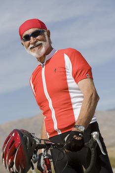 Portrait of a smiling male cyclist standing by bicycle