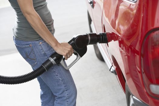 Mid section of a woman refueling her car at a service station