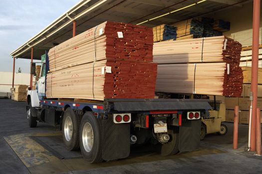 Truck loaded with wooden planks in front of warehouse