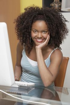 Portrait of a happy young African American woman working on desktop PC
