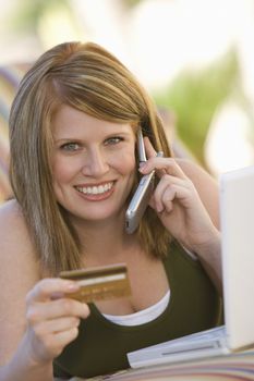 Portrait of a woman shopping online with credit card and cell phone