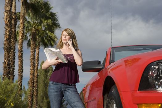 Woman with road map on call standing beside car