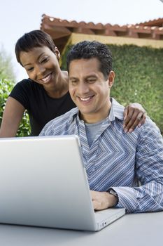 Happy couple with mature man using laptop