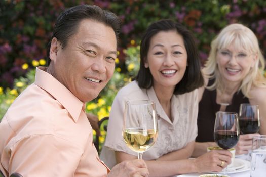 Portrait of happy senior man with female friends celebrating with wine