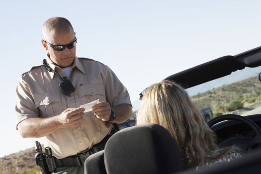 Mature police man checking woman's license