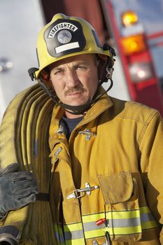 Portrait of a confident fire fighter holding hose on shoulder