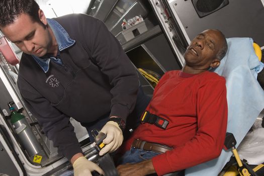 Male EMT professional taking care of a senior man inside ambulance