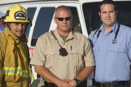 Portrait of confident firefighter, traffic cop and EMT doctor standing together