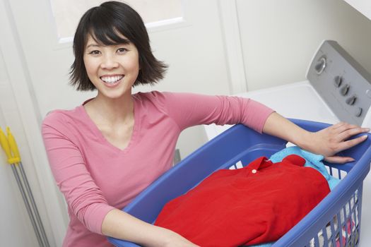 Portrait of a happy Asian housewife holding a basket of clothes to wash