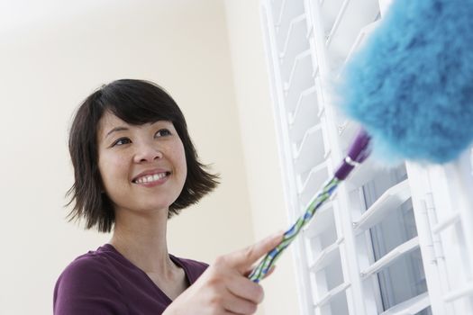 Closeup of a smiling Asian woman dusting window