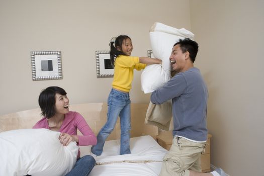Cheerful family having pillow fight in a bedroom