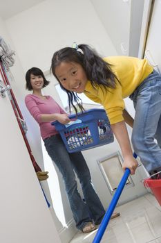 Portrait of daughter helping mother in cleaning floor