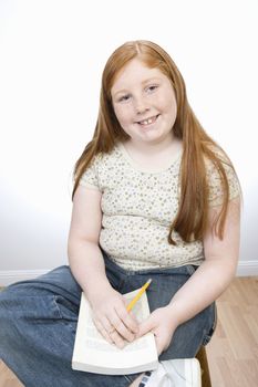 Portrait of happy teenage girl studying while sitting on floor