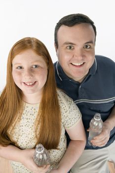 Portrait of happy father and daughter holding water bottle