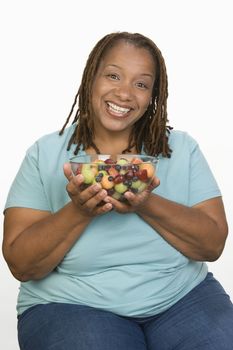 Portrait of Mid-adult overweight  woman holding bowl wit fruit salad and smiling