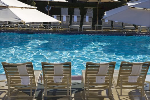 View of swimming pool with lounge chairs and sunshades