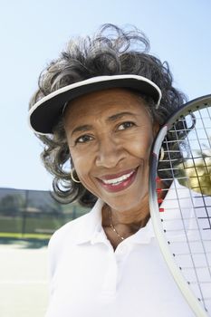 Close-up of happy senior woman holding tennis racquet