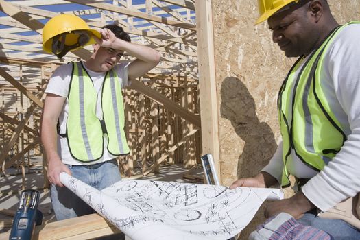 Manual workers with blueprint at construction site