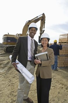 Portrait of two engineers with blueprint at construction site