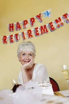Portrait of happy senior woman sitting with cake in foreground