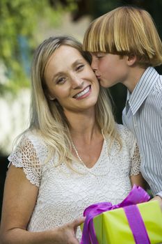 Portrait of happy mother getting kiss from son at birthday