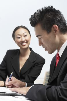 Businessman signing a contract with partner smiling in the background