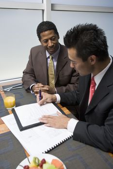 An Asian businessman signing contract with African American businessman