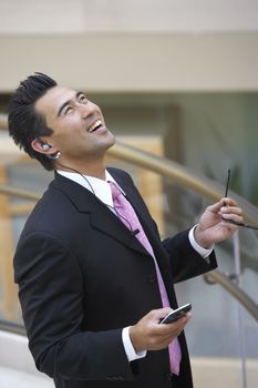 Excited Japanese businessman holding mobile phone and looking up