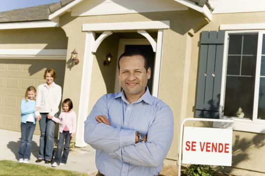 Portrait of happy mature man with family standing in front of new house