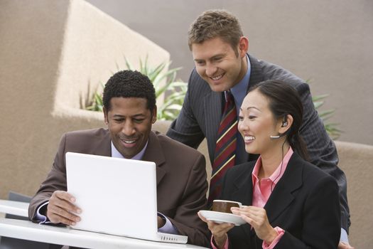 Multi ethnic business people smiling while looking at laptop during their coffee break
