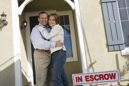 Happy mature couple embracing in front of new house