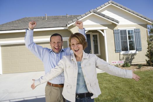 Portrait of cheerful couple standing in front of new house