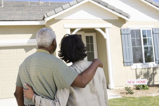 Rear view of African American couple standing in front of new house