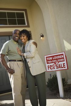 Portrait of happy senior African American couple standing in front of new house