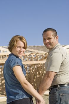 Portrait of happy mature couple in front of house under construction
