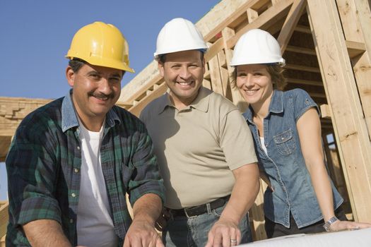 Portrait of three architects with blueprint at construction site
