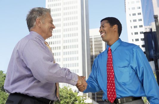 Two happy successful businessmen shaking hands for a deal