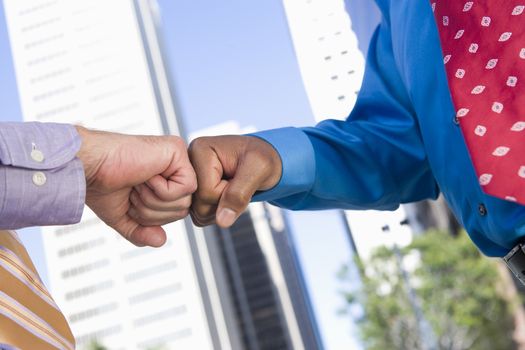 Closeup of two hands punching fists with building in the background