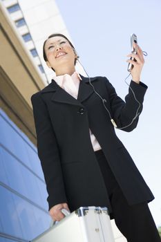 Low angle view of happy Asian businesswoman using cell phone with building in the background