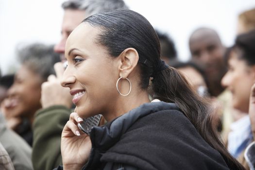 Closeup side view of an African American woman using cellphone in blurred crowd